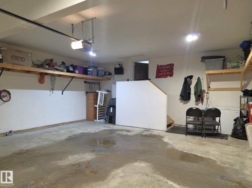 The property features a garage with a concrete floor, overhead lighting, and built-in wall shelving for storage - 4477 36 Street, Drayton Valley, AB - Indoor Photo Showing Garage