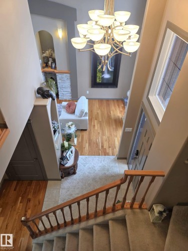 The property features a grand foyer with a large chandelier, a window providing natural light, and a staircase with a wooden banister - 4477 36 Street, Drayton Valley, AB - Indoor Photo Showing Other Room