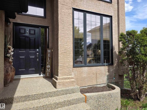 Stucco exterior featuring a prominent black panel door with sidelight - 4477 36 Street, Drayton Valley, AB - Outdoor With Exterior