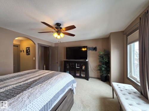 This bedroom features a ceiling fan with light fixture, carpeted flooring, and a large window with blinds and drapes - 4477 36 Street, Drayton Valley, AB - Indoor Photo Showing Bedroom