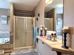 Bathroom featuring a glass-enclosed shower with tiled walls, a corner bathtub, and a spacious vanity with a large mirror - 