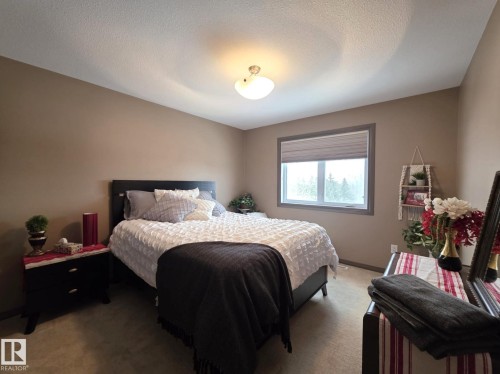 This room features a window with blinds, carpeted flooring, and a ceiling light fixture - 4477 36 Street, Drayton Valley, AB - Indoor Photo Showing Bedroom