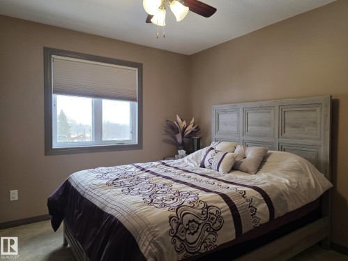 Comfortable room featuring a ceiling fan with integrated lighting, a window with a cellular blind, and a bed with a detailed headboard - 4477 36 Street, Drayton Valley, AB - Indoor Photo Showing Bedroom
