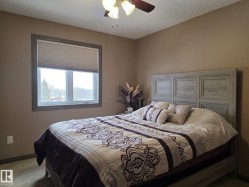 Comfortable room featuring a ceiling fan with integrated lighting, a window with a cellular blind, and a bed with a detailed headboard - 