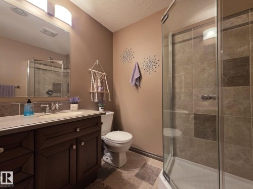 The bathroom features a vanity with a countertop and undermount sink, a toilet, and a tiled shower with a clear glass enclosure - 4477 36 Street, Drayton Valley, AB - Indoor Photo Showing Bathroom