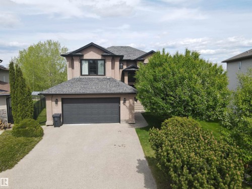 Two-story stucco exterior featuring a dark asphalt shingle roof and a prominent dark garage door - 4477 36 Street, Drayton Valley, AB - Outdoor