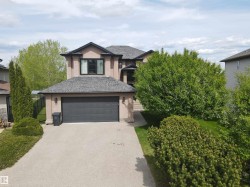 Two-story stucco exterior featuring a dark asphalt shingle roof and a prominent dark garage door - 