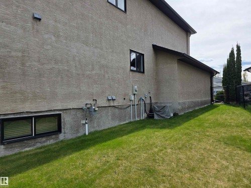 Stucco exterior with a lower level window and a grassy yard - 4477 36 Street, Drayton Valley, AB - Outdoor With Exterior