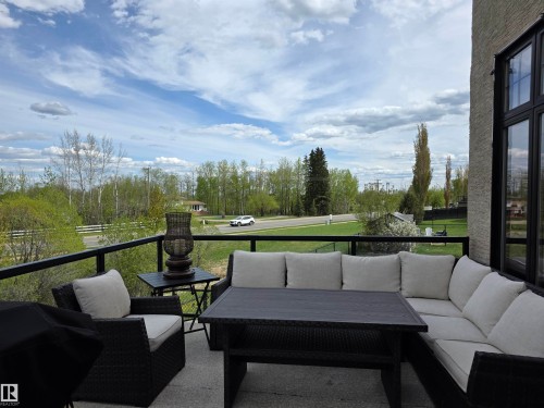 Private balcony featuring a glass and metal railing, concrete flooring, and extensive natural greenery beyond - 4477 36 Street, Drayton Valley, AB - Outdoor With Deck Patio Veranda
