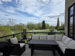 Private balcony featuring a glass and metal railing, concrete flooring, and extensive natural greenery beyond - 
