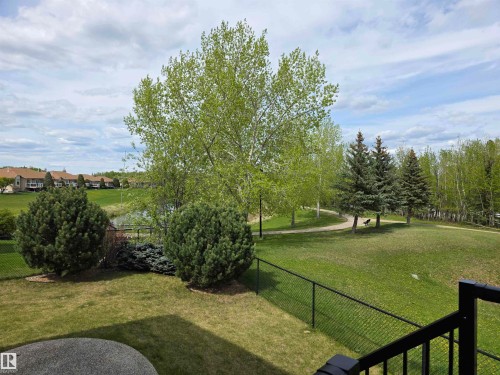 Expansive backyard featuring a manicured lawn, established trees, and a black chain-link fence - 4477 36 Street, Drayton Valley, AB - Outdoor With View