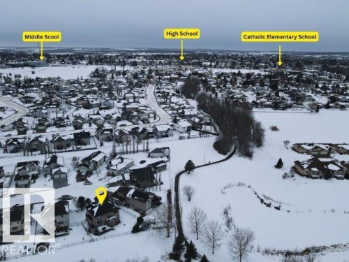 Aerial view of the property and its surrounding community, featuring a residential neighborhood with various homes and a paved pathway - 4477 36 Street, Drayton Valley, AB - 