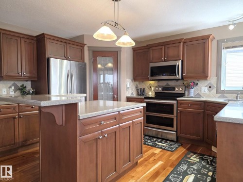 The property features a kitchen with wood cabinetry, stainless steel appliances, and light-colored countertops - 4477 36 Street, Drayton Valley, AB - Indoor Photo Showing Kitchen