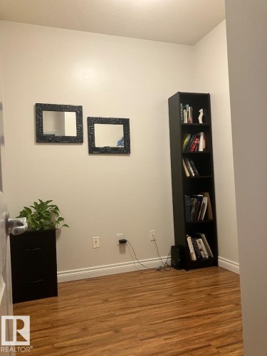 This room features wood-look flooring and light-colored walls - 145 10121 80 Avenue, Edmonton, AB - Indoor Photo Showing Other Room