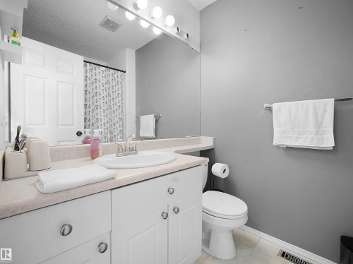 Bathroom featuring a vanity with a countertop and an integrated sink, a mirror, and a toilet - 13040 34 Street, Edmonton, AB - Indoor Photo Showing Bathroom