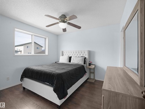 The room features wood flooring, light blue walls, and a ceiling fan with integrated lighting - 13040 34 Street, Edmonton, AB - Indoor Photo Showing Bedroom