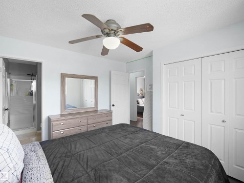 This room features a ceiling fan with light fixture, light blue walls, and white bi-fold closet doors - 13040 34 Street, Edmonton, AB - Indoor Photo Showing Bedroom