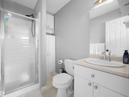 The bathroom features a glass-enclosed shower, a white vanity with a countertop and sink, and a toilet - 13040 34 Street, Edmonton, AB - Indoor Photo Showing Bathroom