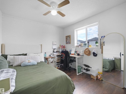 The room features a window providing natural light, a ceiling fan, and dark wood-style flooring - 13040 34 Street, Edmonton, AB - Indoor Photo Showing Bedroom