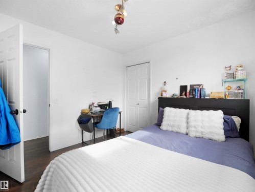 This room features dark wood flooring, white walls, and a white door with a black handle - 13040 34 Street, Edmonton, AB - Indoor Photo Showing Bedroom