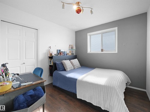 This room features hardwood flooring, a window providing natural light, and a white paneled door - 13040 34 Street, Edmonton, AB - Indoor Photo Showing Bedroom