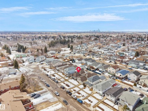 Aerial view of the property and surrounding neighborhood, featuring residential homes, paved roads, and a visible skyline in the distance - 13040 34 Street, Edmonton, AB - Outdoor With View