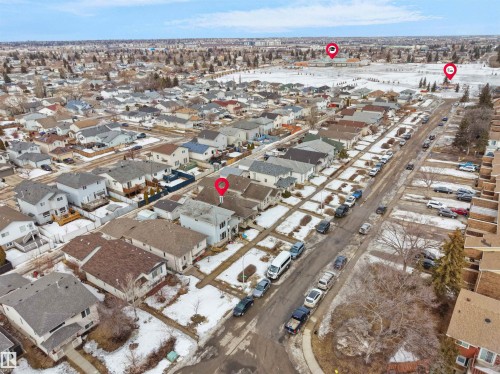 Aerial view of the surrounding residential neighborhood with detached properties, street parking, and a large open field in the distance - 13040 34 Street, Edmonton, AB - Outdoor With View