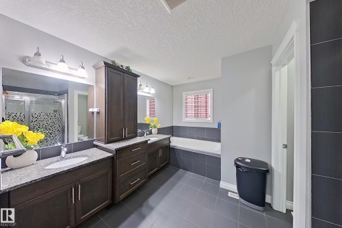 Spacious bathroom featuring a double vanity with granite countertops, dark wood cabinetry, a built-in bathtub, and a separate shower with a glass enclosure - 1743 60 Street Sw, Edmonton, AB - Indoor Photo Showing Bathroom