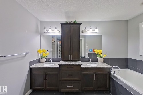 Bathroom featuring a double vanity with dark wood cabinetry, granite countertops, and two undermount sinks - 1743 60 Street Sw, Edmonton, AB - Indoor Photo Showing Bathroom