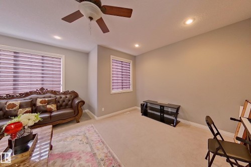 This living space features light-colored carpeting, two windows with horizontal blinds, and recessed lighting in the ceiling - 1743 60 Street Sw, Edmonton, AB - Indoor