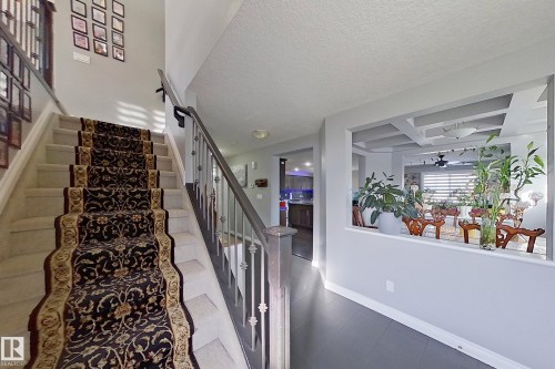 The property features a staircase with a patterned runner, and a half-wall opening that provides a view into an adjacent area with a coffered ceiling - 1743 60 Street Sw, Edmonton, AB - Indoor Photo Showing Other Room