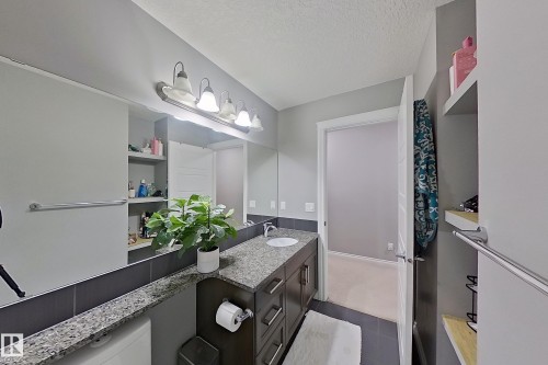This bathroom features a vanity with a granite countertop, a single basin sink, and ample storage cabinets - 1743 60 Street Sw, Edmonton, AB - Indoor Photo Showing Bathroom