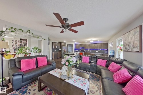 The living area features a ceiling fan, a large window with blinds, and hardwood flooring - 1743 60 Street Sw, Edmonton, AB - Indoor Photo Showing Living Room