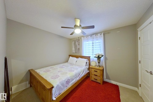 This room features a ceiling fan, a window with blinds and curtains, and a solid-panel door - 1743 60 Street Sw, Edmonton, AB - Indoor Photo Showing Bedroom