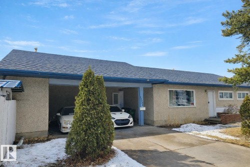The property features a car port, a paved driveway, a white fence, and a pitched roof with blue gutters - 13204 131A Avenue, Edmonton, AB - Outdoor