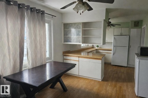 This space features hardwood flooring, white kitchen cabinetry with light-colored countertops, and a ceiling fan - 13204 131A Avenue, Edmonton, AB - Indoor Photo Showing Kitchen