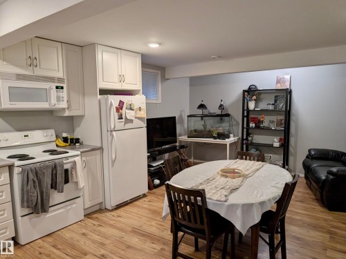 The property features a kitchen area with white cabinetry, a white microwave, and a white refrigerator - 10645 65 Avenue, Edmonton, AB - Indoor Photo Showing Kitchen