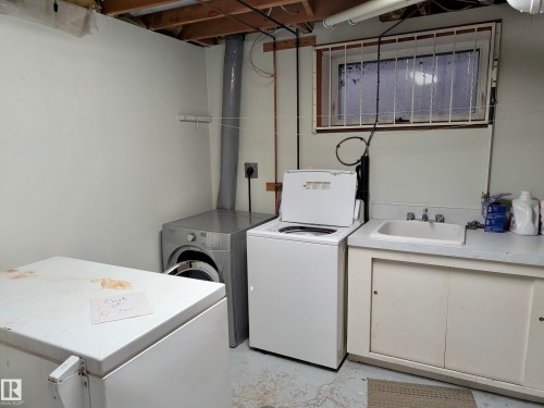 Laundry area featuring a utility sink, countertop space, and under-sink cabinetry - 10645 65 Avenue, Edmonton, AB - Indoor Photo Showing Laundry Room