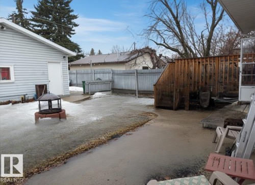 The property features a spacious yard with a concrete patio area, a wooden fence, and a detached structure with light-colored siding - 10645 65 Avenue, Edmonton, AB - Outdoor