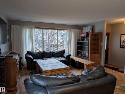 The living area features a large window with white curtains, providing natural light, and light-colored walls - 10645 65 Avenue, Edmonton, AB - Indoor Photo Showing Living Room
