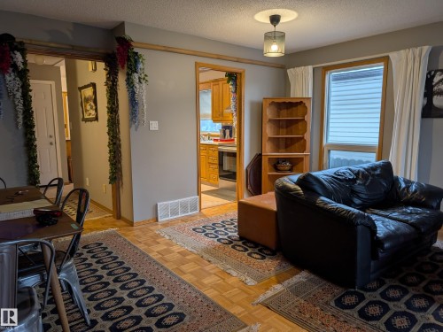This inviting living area features warm-toned hardwood flooring, a window with blinds, and a ceiling-mounted light fixture - 10645 65 Avenue, Edmonton, AB - Indoor