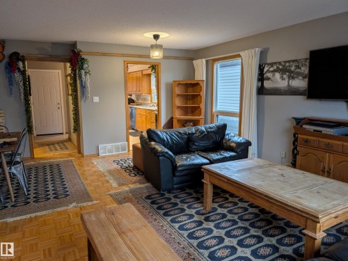 This living area features a light fixture, parquet flooring, and a large window - 10645 65 Avenue, Edmonton, AB - Indoor Photo Showing Living Room
