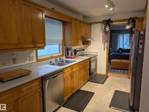 The kitchen features wood cabinetry, a double basin sink, and a dishwasher - 10645 65 Avenue, Edmonton, AB - Indoor Photo Showing Kitchen With Double Sink