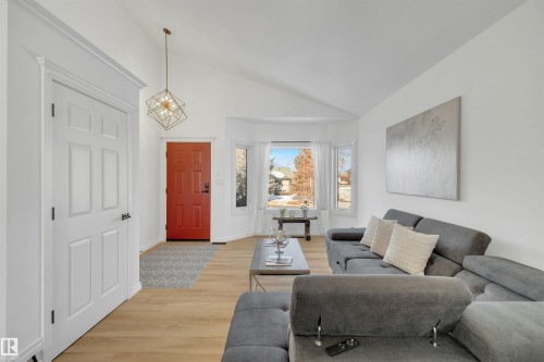 The inviting living area features light-toned flooring, a bright red entry door, a bay window, and a vaulted ceiling - 131 West Liberty Crescent, Millet, AB - Indoor Photo Showing Living Room