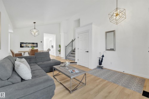 The property features light wood flooring, white walls, and a staircase with grey carpeting - 131 West Liberty Crescent, Millet, AB - Indoor Photo Showing Living Room