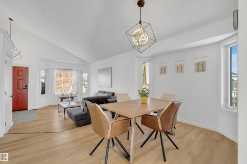 This bright interior features vaulted ceilings, light wood-look flooring, and a red front door - 131 West Liberty Crescent, Millet, AB - Indoor Photo Showing Dining Room