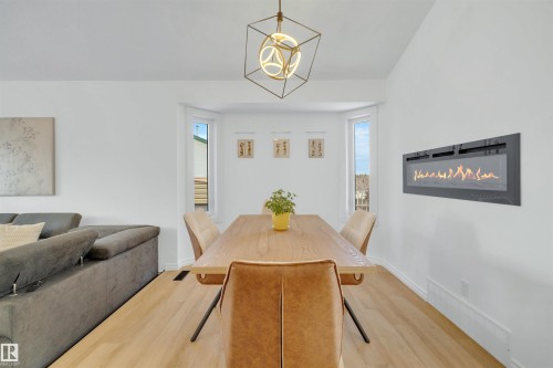 This inviting space features a modern fireplace, light-toned flooring, and a contemporary light fixture - 131 West Liberty Crescent, Millet, AB - Indoor Photo Showing Dining Room