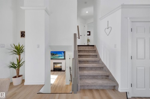 The property features a staircase with carpeted treads and a modern railing, and light-colored flooring visible on the lower level - 131 West Liberty Crescent, Millet, AB - Indoor Photo Showing Other Room