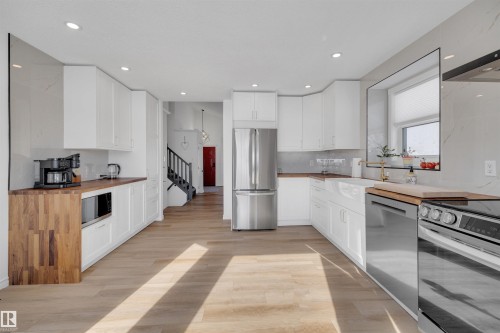 Spacious kitchen featuring white cabinetry, light wood flooring, wood countertops, and stainless steel appliances - 131 West Liberty Crescent, Millet, AB - Indoor Photo Showing Kitchen