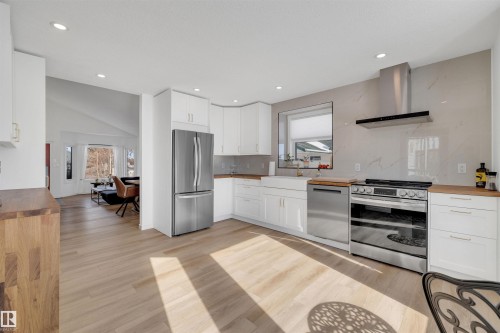 Well-appointed kitchen featuring hardwood flooring, white cabinetry, stainless steel appliances, and wood countertops - 131 West Liberty Crescent, Millet, AB - Indoor Photo Showing Kitchen With Upgraded Kitchen